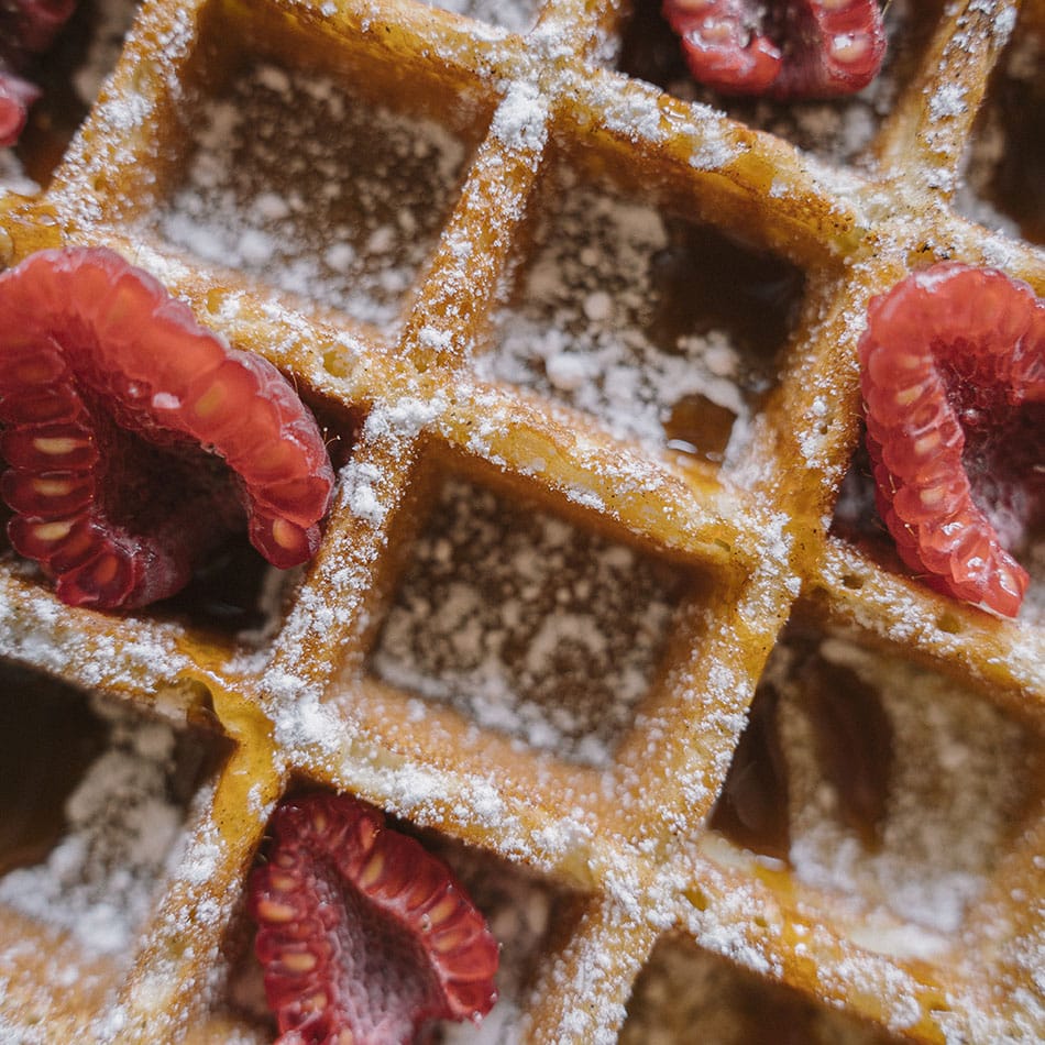 Gaufre géante avec du sucre glace, des framboises et du caramel au beurre salé
