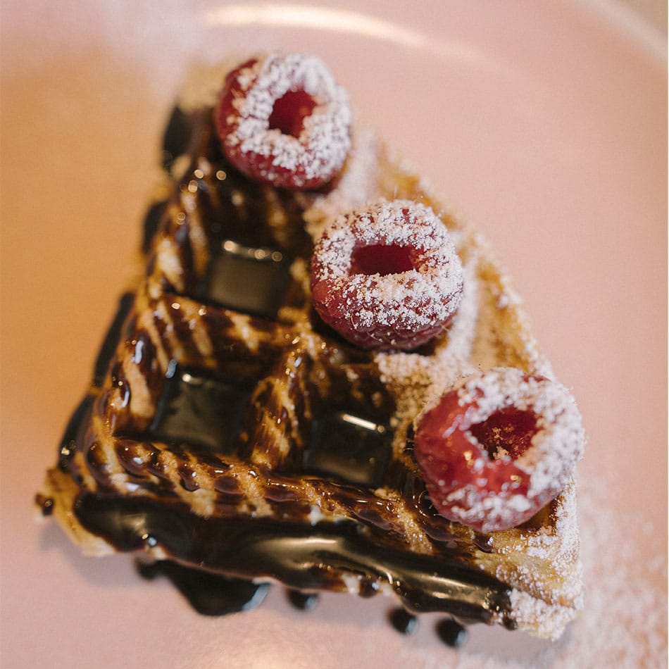 Gaufre au chocolat coulant et à la framboise, posée sur une assiette rose