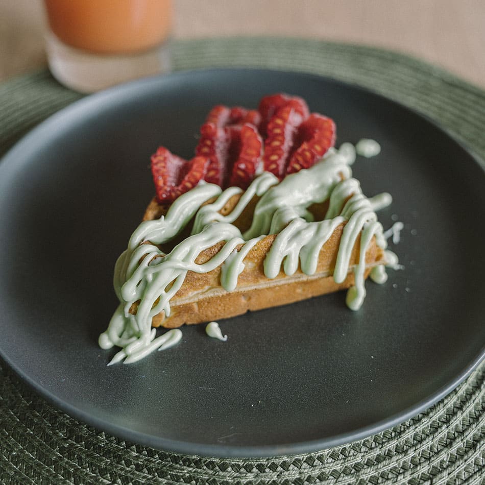Gaufre ronde au matcha et à la framboise, posée sur une assiette